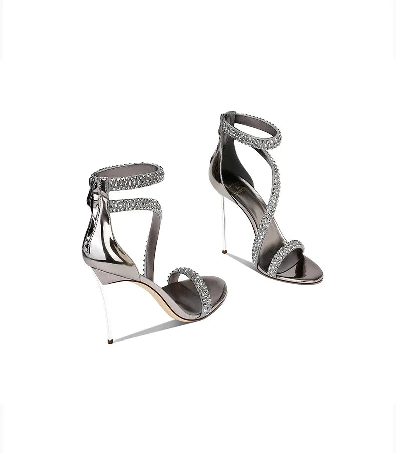 Pair of silver high-heeled sandals with gemstone embellishments on a white background