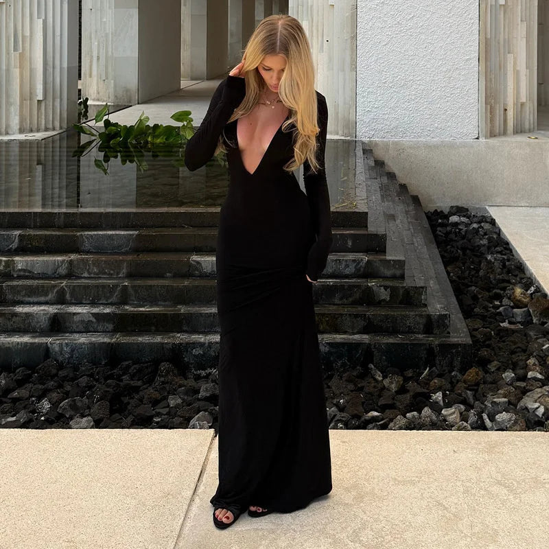 Woman in a black dress standing on a stone path with steps and plants in the background