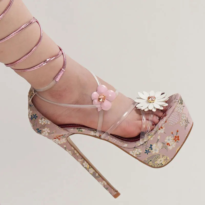 Pink high-heeled sandals with floral design on a light gray background