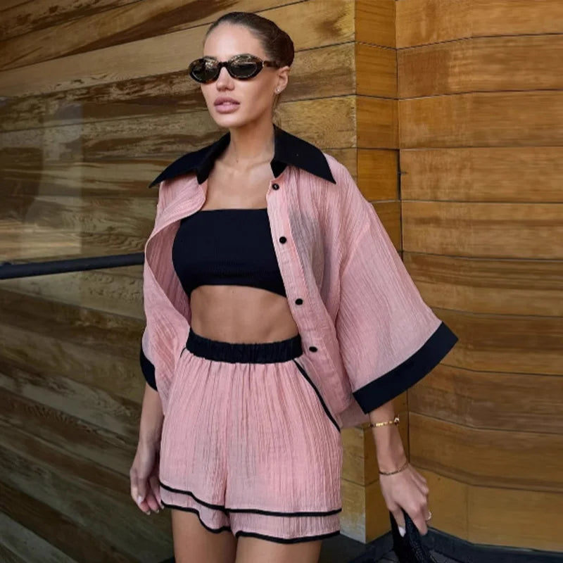 Woman wearing a pink outfit with black trim against a wooden wall.