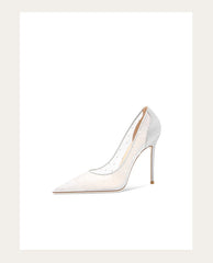 White high-heeled shoe with gold accents on a light beige background