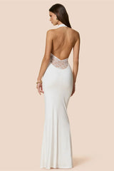 Woman wearing a white evening gown with lace detailing on a beige background