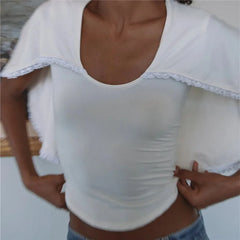 Woman adjusting U-neck knit top with white lace trim cape overlay