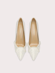 Pair of white pointed-toe shoes with lace detailing on a light gray background