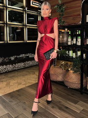 Woman in a red dress standing in a bar setting with bottles and decor.