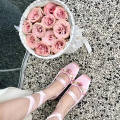Close-up of pink ballet flats with floral details and ribbon ties