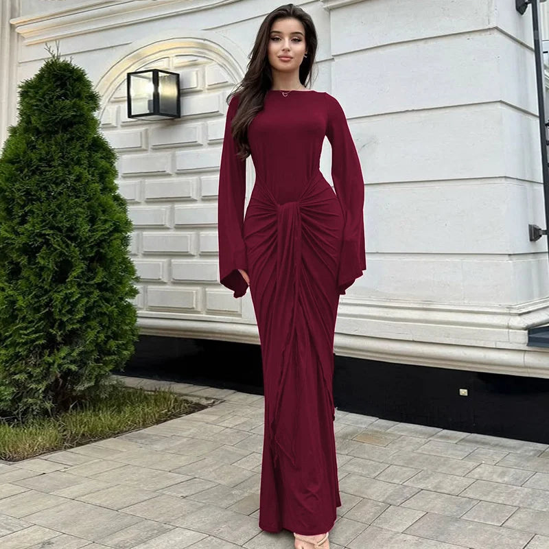 Woman in a burgundy dress standing in front of a white building.