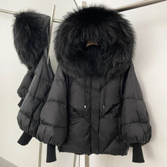Black puffer jacket with large fur hood on a rack against a white background