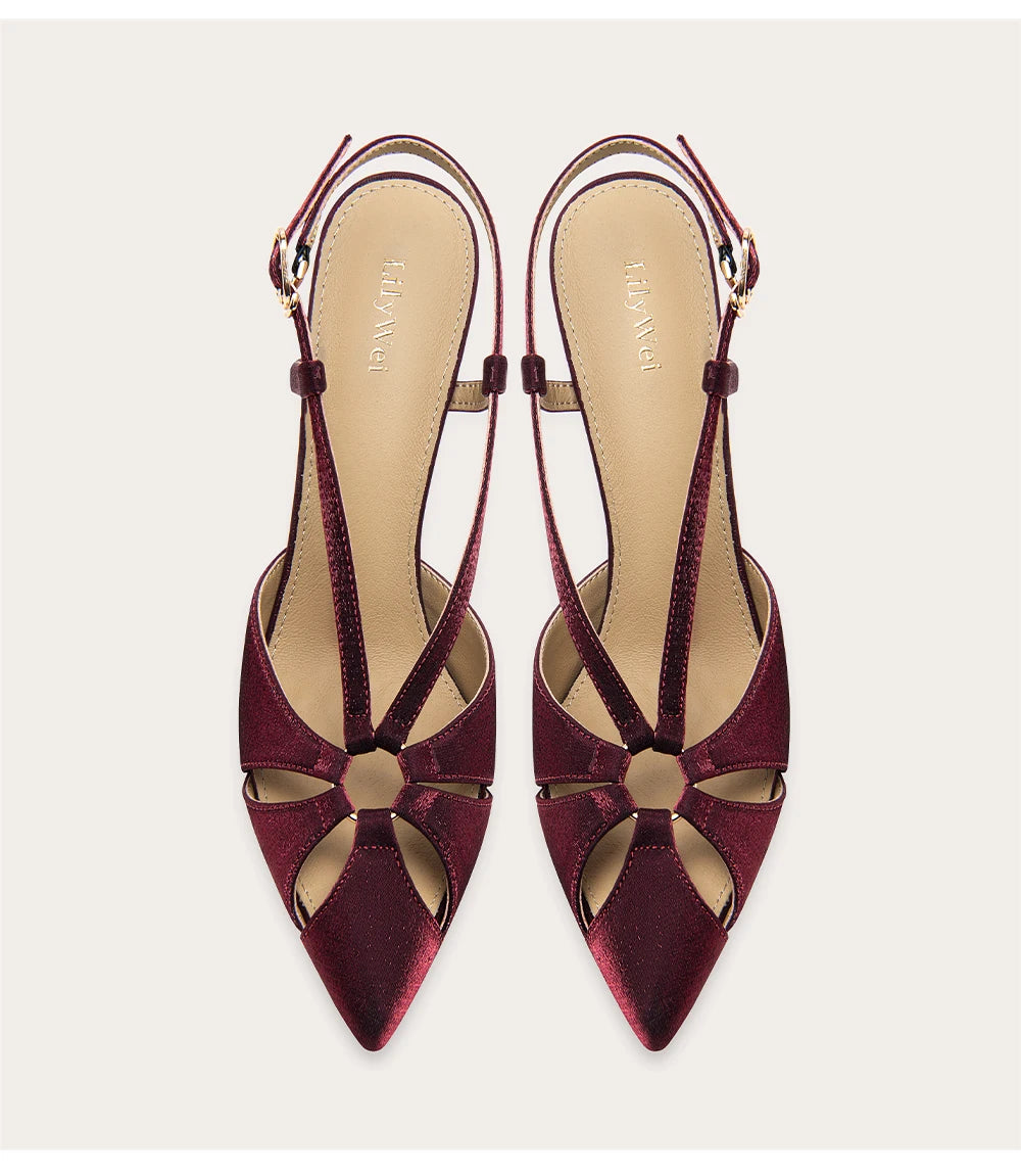 Pair of burgundy high-heeled shoes with cut-out design on a light gray background