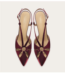 Pair of burgundy high-heeled shoes with cut-out design on a light gray background