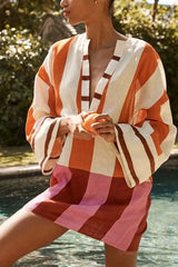 Woman wearing a striped v-neck mini dress with bell sleeves by a pool
