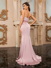 Woman in a pink evening gown standing in an ornate room with mirrors.