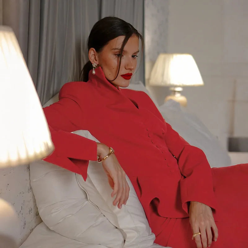 Woman in a red outfit sitting on a couch in a softly lit room.