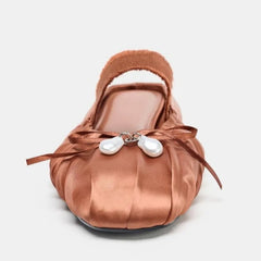 Front view of a pleated satin mule flat with pearl and bow detail.