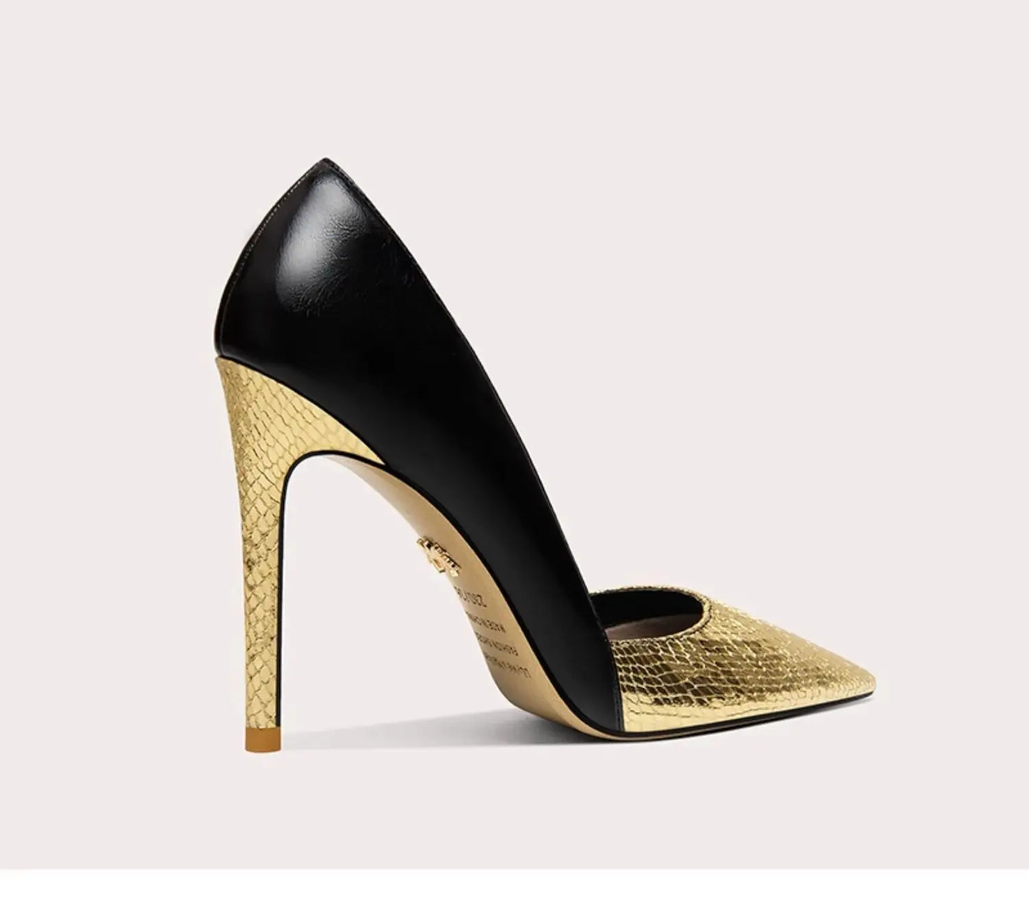 Black and gold high-heeled shoe on a light gray background