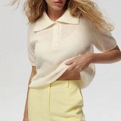 Woman wearing a cream-colored knit top and yellow pants on a plain background