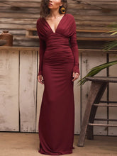 Woman wearing a burgundy evening gown in a rustic setting