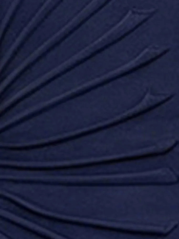 Close-up of the asymmetrical ruched fabric detail on a navy dress