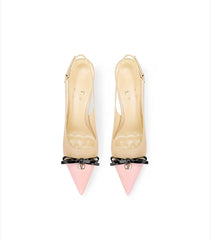Beige high-heeled shoes with pink tips and black bow details on a white background