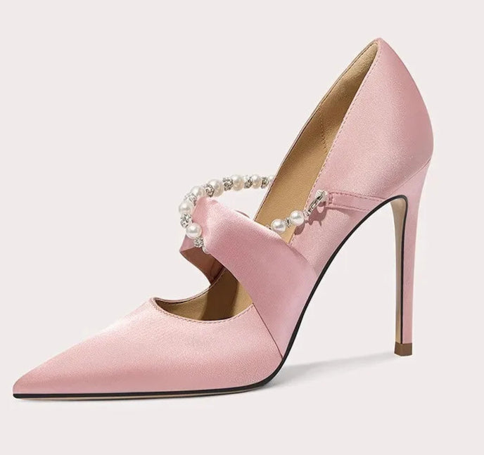 Pink high-heeled shoe with pearl embellishments on a light gray background