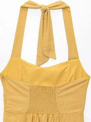 Yellow dress with smocked bodice and tied straps on a white background