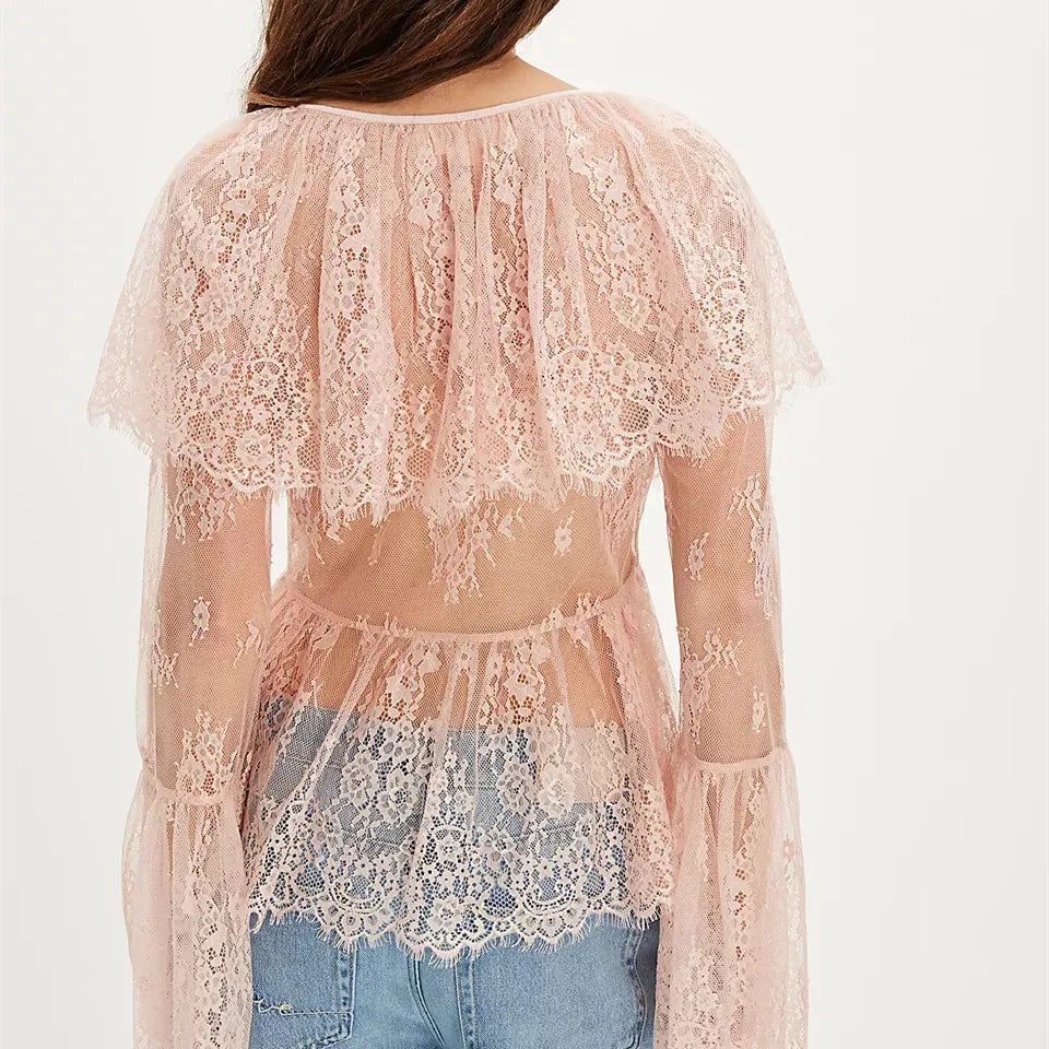 Pink lace top worn over denim jeans on a white background