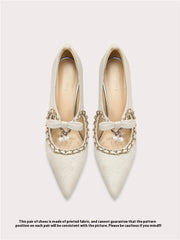 Pair of white pointed-toe shoes with decorative bows and chains on a light gray background.
