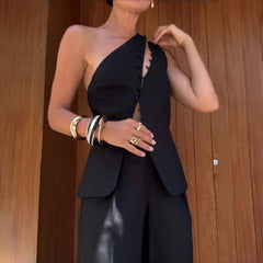 Person wearing a black one-shoulder outfit with a wooden background