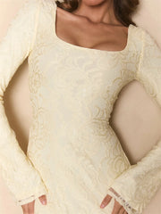 Close-up of a person wearing a cream-colored lace dress with long sleeves.