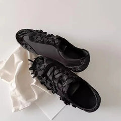 Black flannelette sneakers with floral embellishments resting on a white cloth.