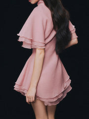 Pink layered dress worn by a person on a black background