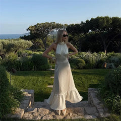 Woman in a white dress standing in a garden with trees and ocean in the background