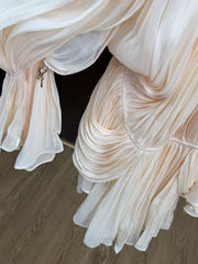 Close-up of a beige fabric with ruffled layers on a wooden floor.