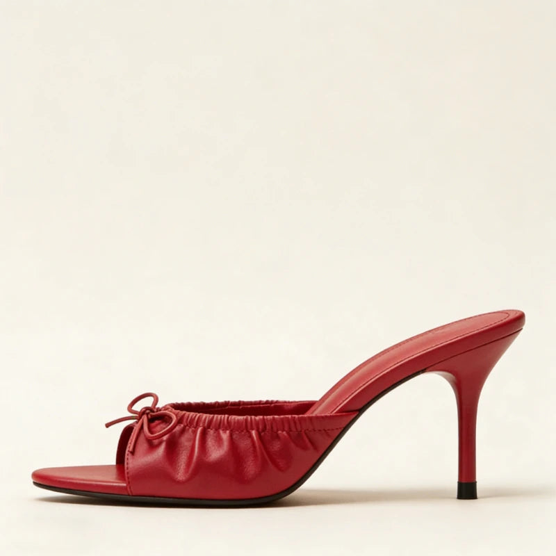 Side profile of a red bow detail stiletto heel slide