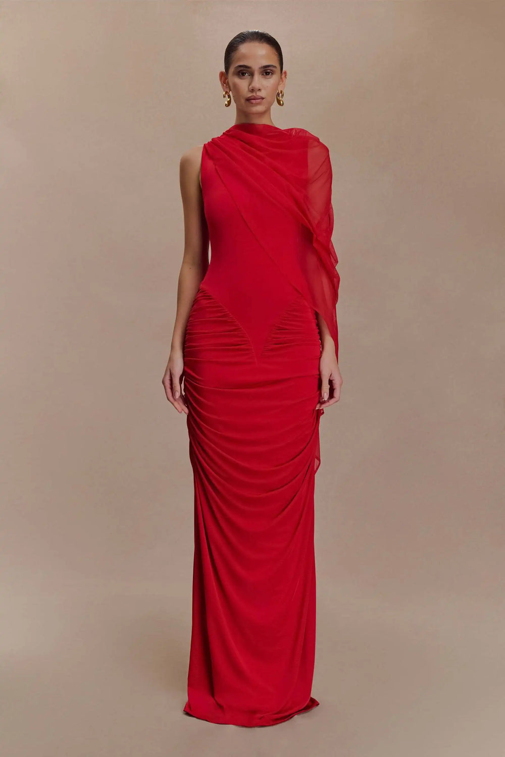 Woman wearing a red evening gown against a beige background