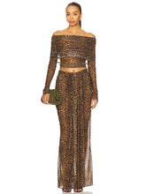 Woman wearing a leopard print off-shoulder top and long skirt with a clutch