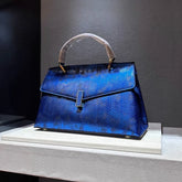 Structured top-handle bag in deep blue with embossed geometric pattern.