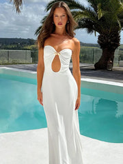 Woman in a white strapless dress standing by a pool with palm trees in the background