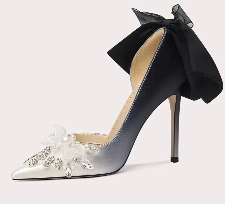 High-heeled shoe with a black bow and floral embellishments on a light gray background