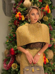 Woman in a gold outfit standing in front of a decorated Christmas tree