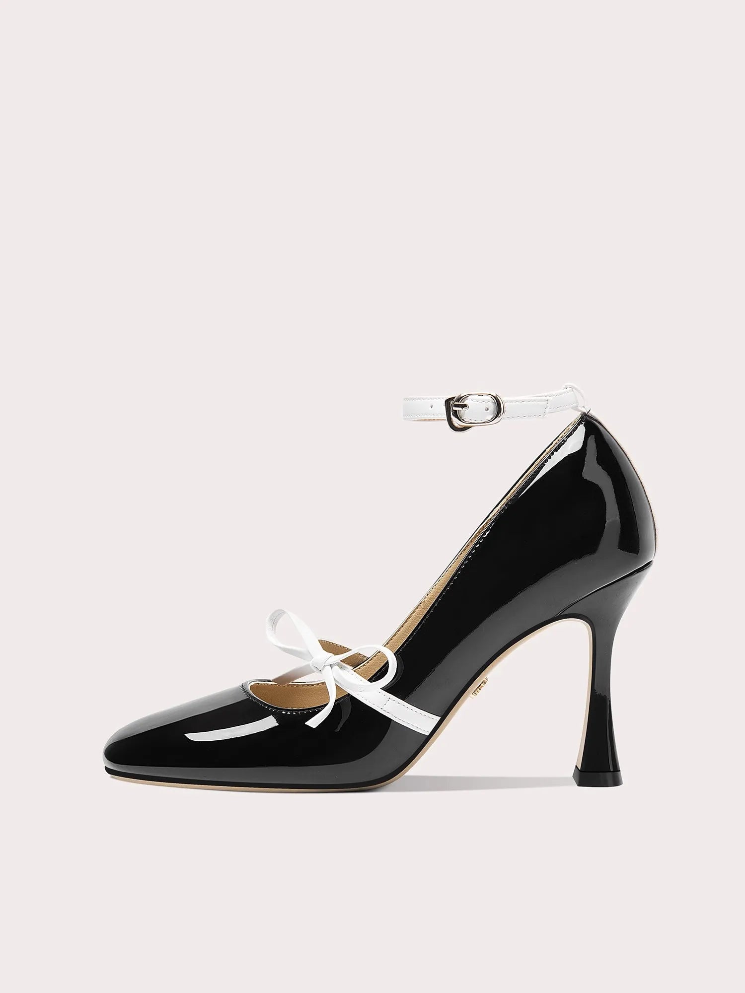 Black patent leather high heel shoe with white laces on a light gray background