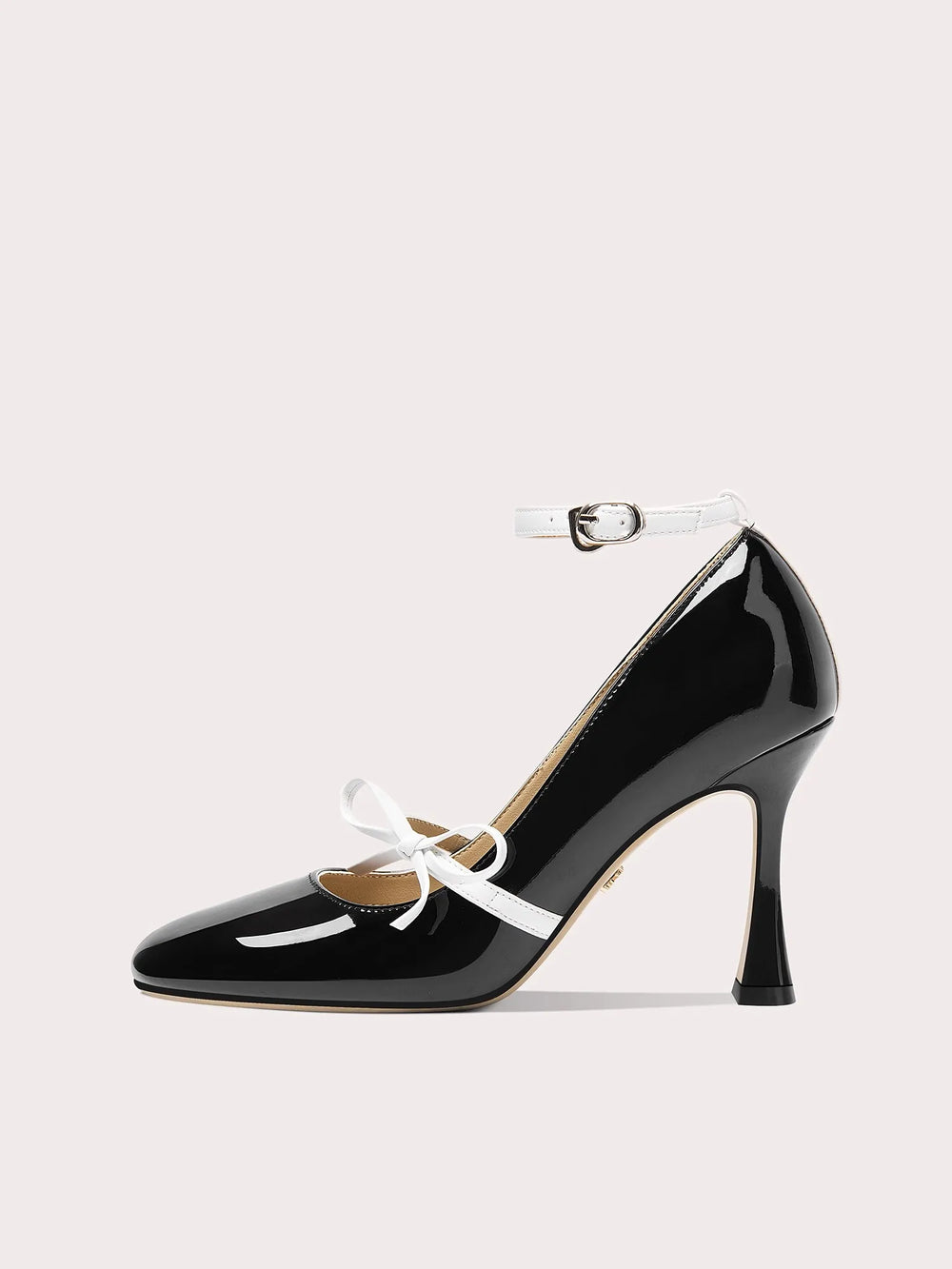 Black patent leather high heel shoe with white laces on a light gray background