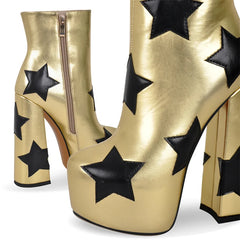 Close-up of metallic gold platform ankle boots with black star appliques and a side zipper.