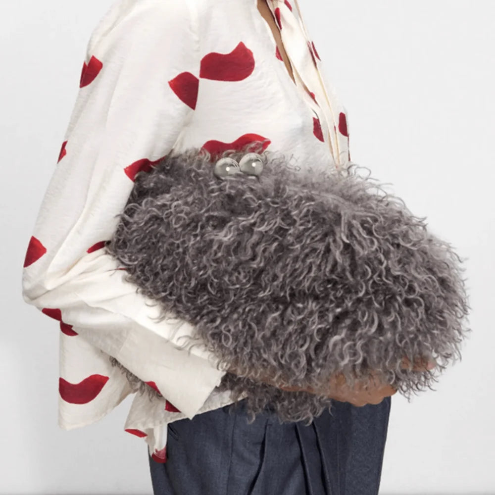 Person holding a fluffy gray bag with a white and red patterned cloth draped over their shoulder.