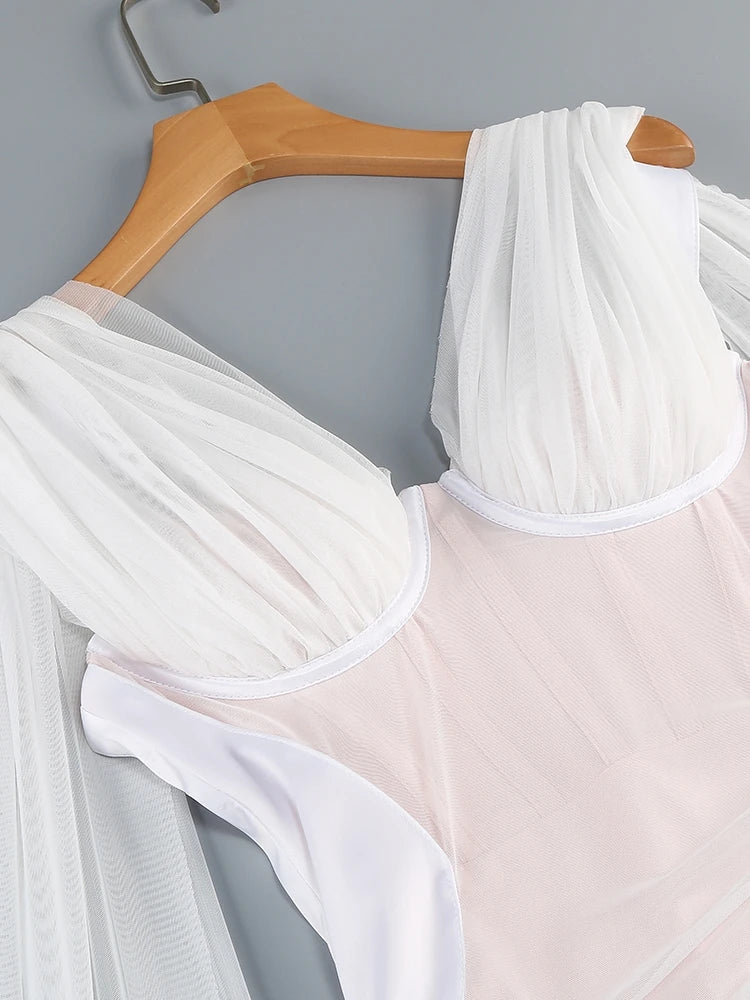 White sheer fabric draped over a pink garment on a wooden hanger against a gray background