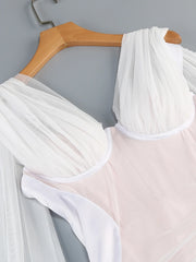 White sheer fabric draped over a pink garment on a wooden hanger against a gray background