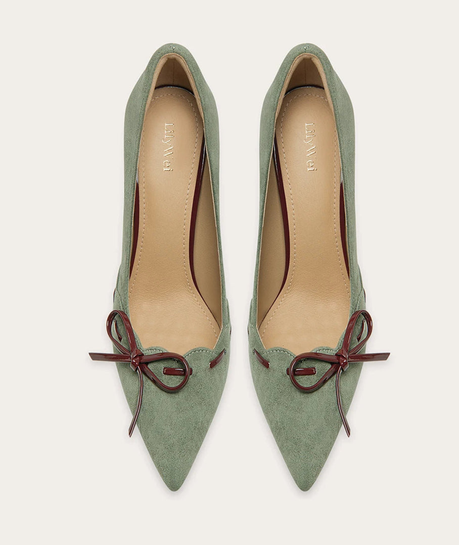 Pair of green high-heeled shoes with brown ribbons on a white background