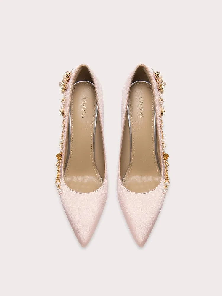 Pair of light pink high-heeled shoes with gold embellishments on a white background