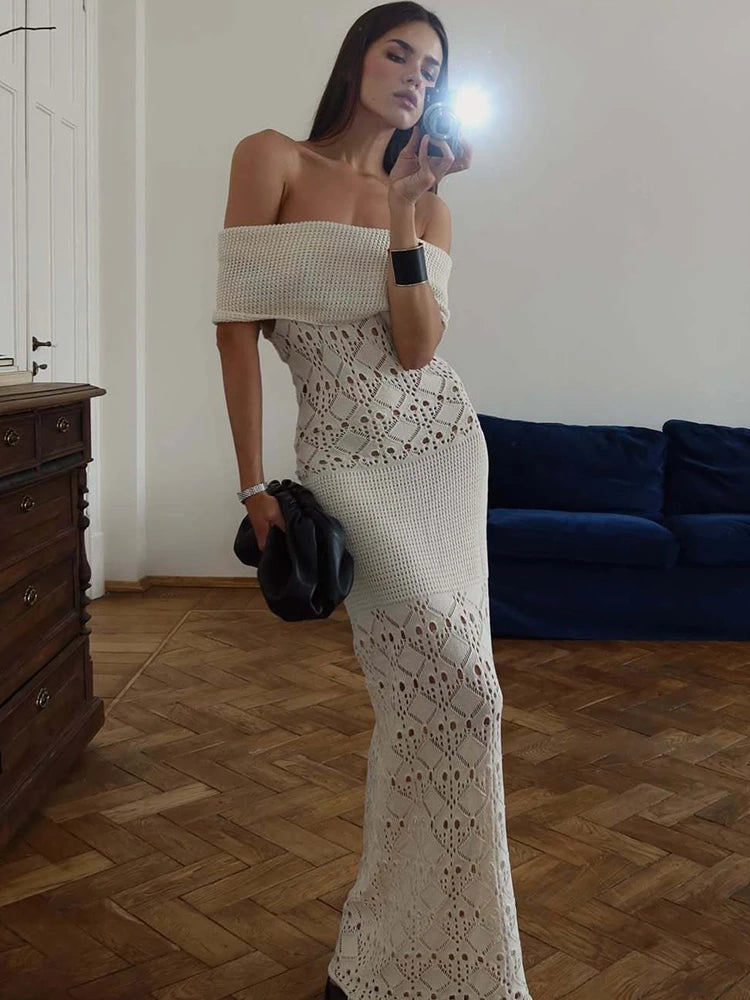 Woman in a white strapless dress taking a mirror selfie in a room with wooden flooring and a blue couch.
