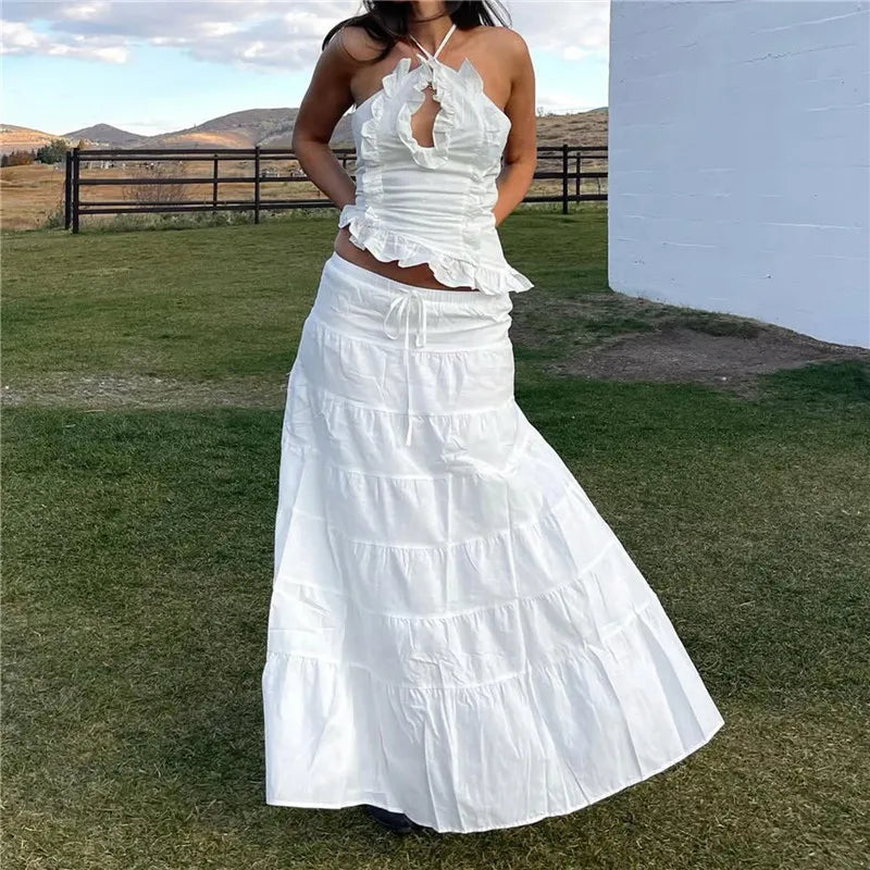 Woman wearing a white ruffled dress standing outdoors with a scenic background